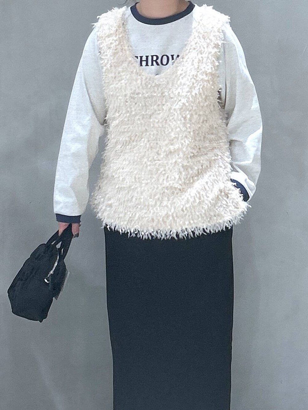 ブラック系のスカート、ホワイト系のベスト、ベージュ系のTシャツ/カットソーを着用したレディースの春コーディネートの2枚目の写真