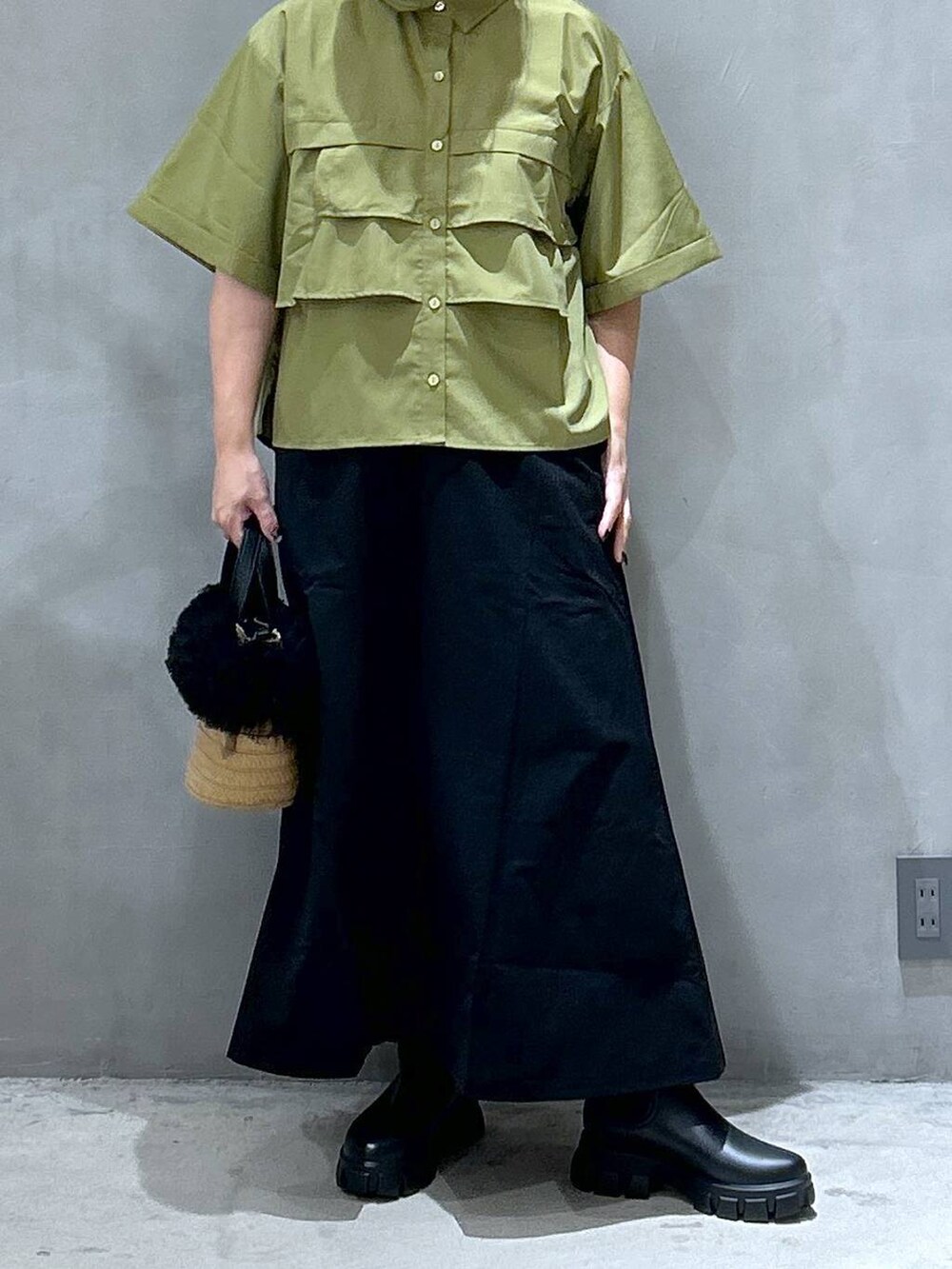 ブラック系のスカート、ベージュ系のショルダーバッグ、ブラック系のレインシューズを着用したレディースの夏コーディネートの5枚目の写真