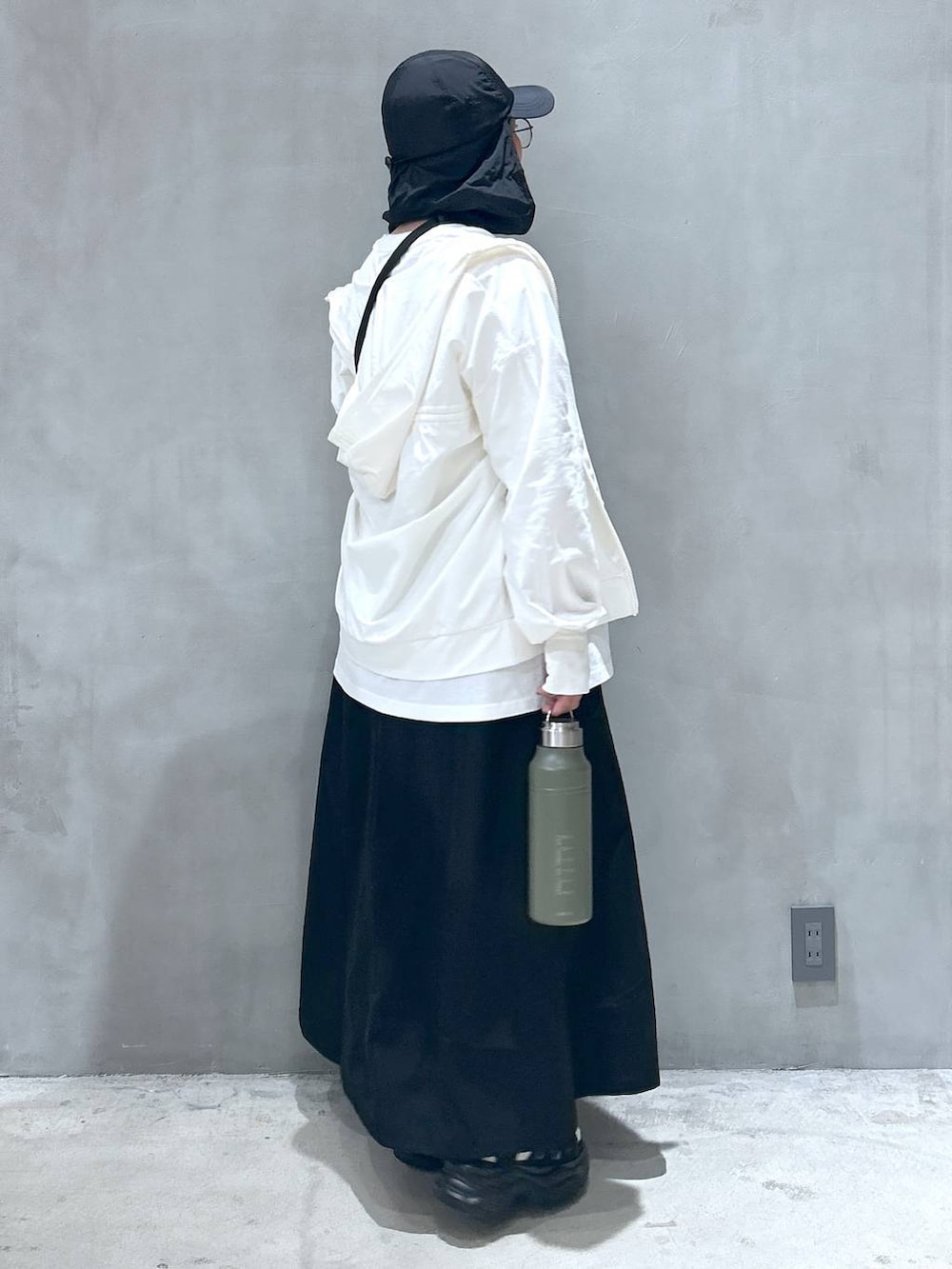 グリーン系のショルダーバッグ、ブラック系のスニーカー、ブラック系のスカートを着用したレディースの春コーディネートの2枚目の写真