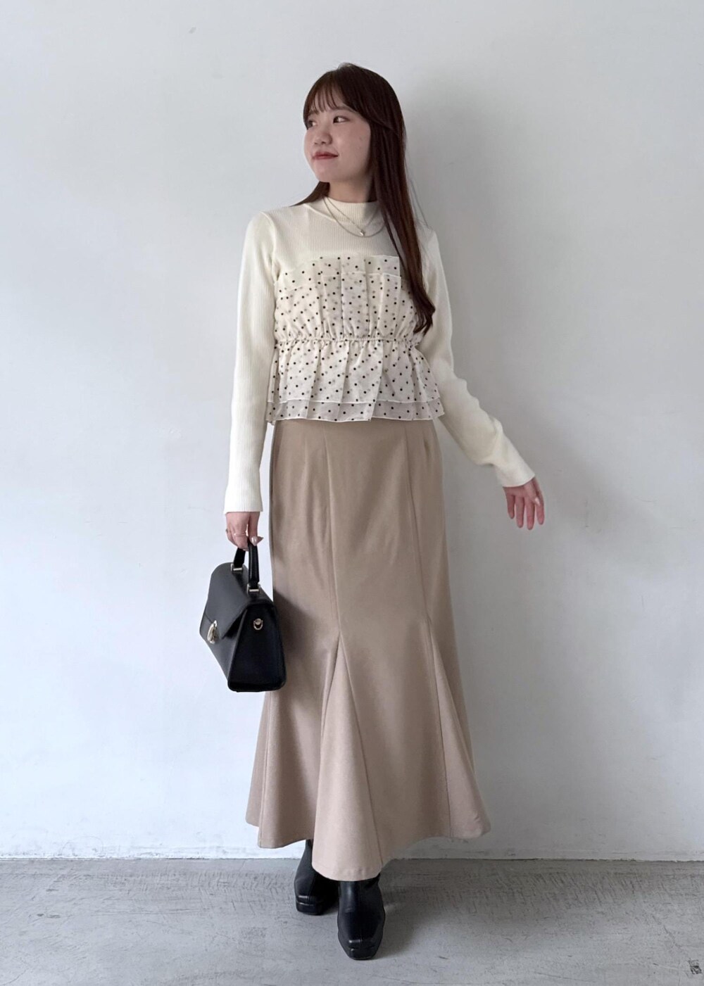 ホワイト系のキャミソール、ベージュ系のスカート、ブラック系のブーツを着用したレディースの秋コーディネートの2枚目の写真