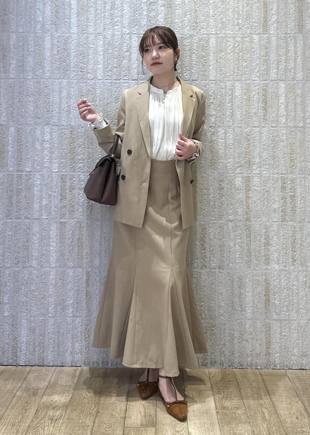 ブラウン系のハンドバッグ、イエロー系のパンプス、ベージュ系のスカートを着用したレディースの秋コーディネートの2枚目の写真