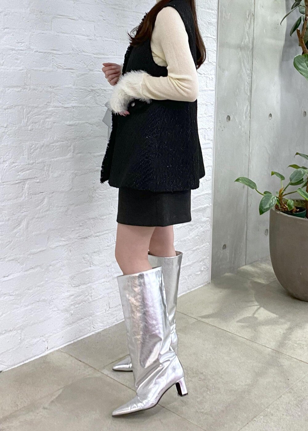 グレー系のその他パンツ、シルバー系のブーツ、ホワイト系のニット/セーターを着用したレディースの冬コーディネートの6枚目の写真