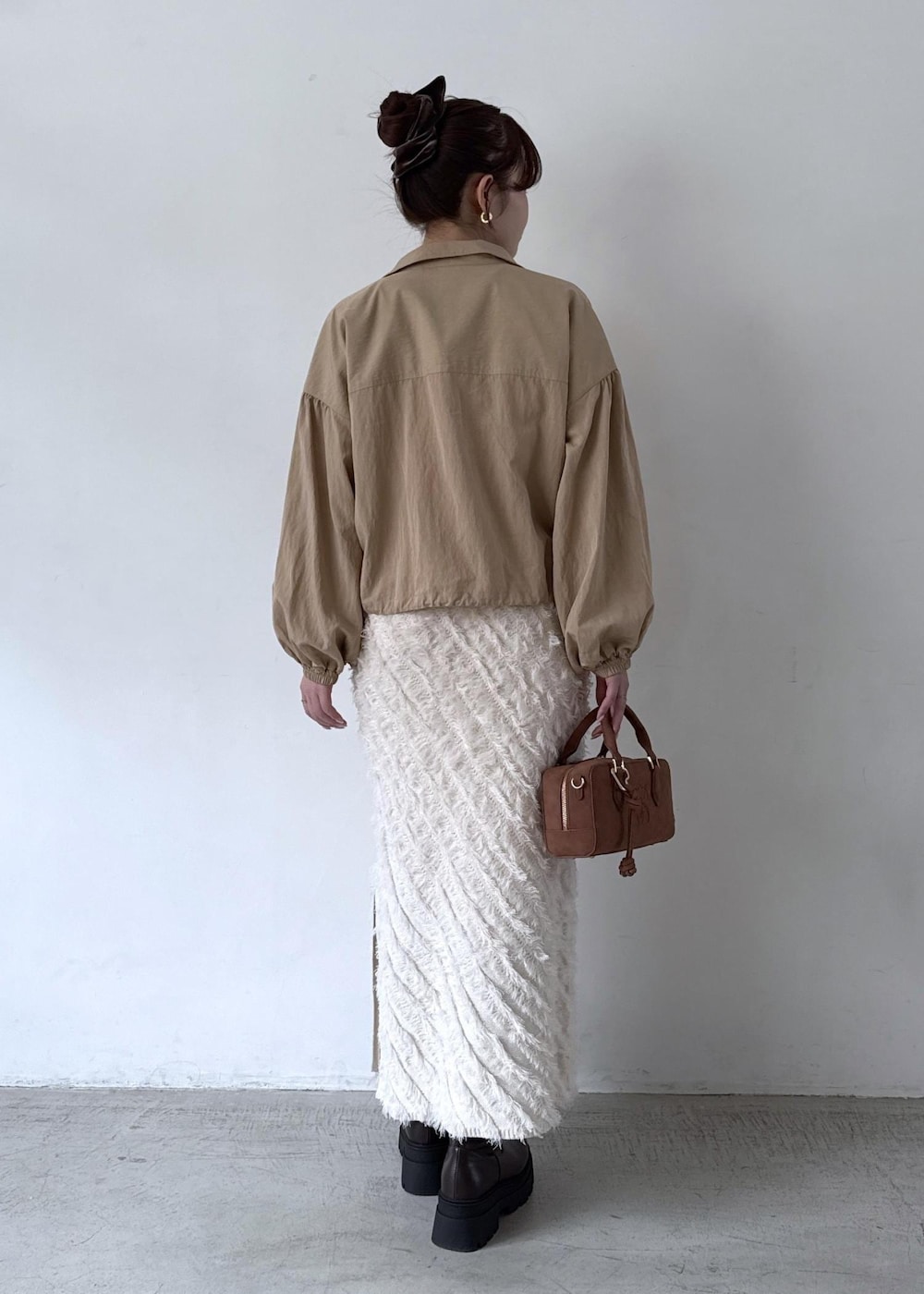 ブラウン系のボストンバッグ、ホワイト系のTシャツ/カットソー、ベージュ系のブルゾンを着用したレディースの秋コーディネートの7枚目の写真