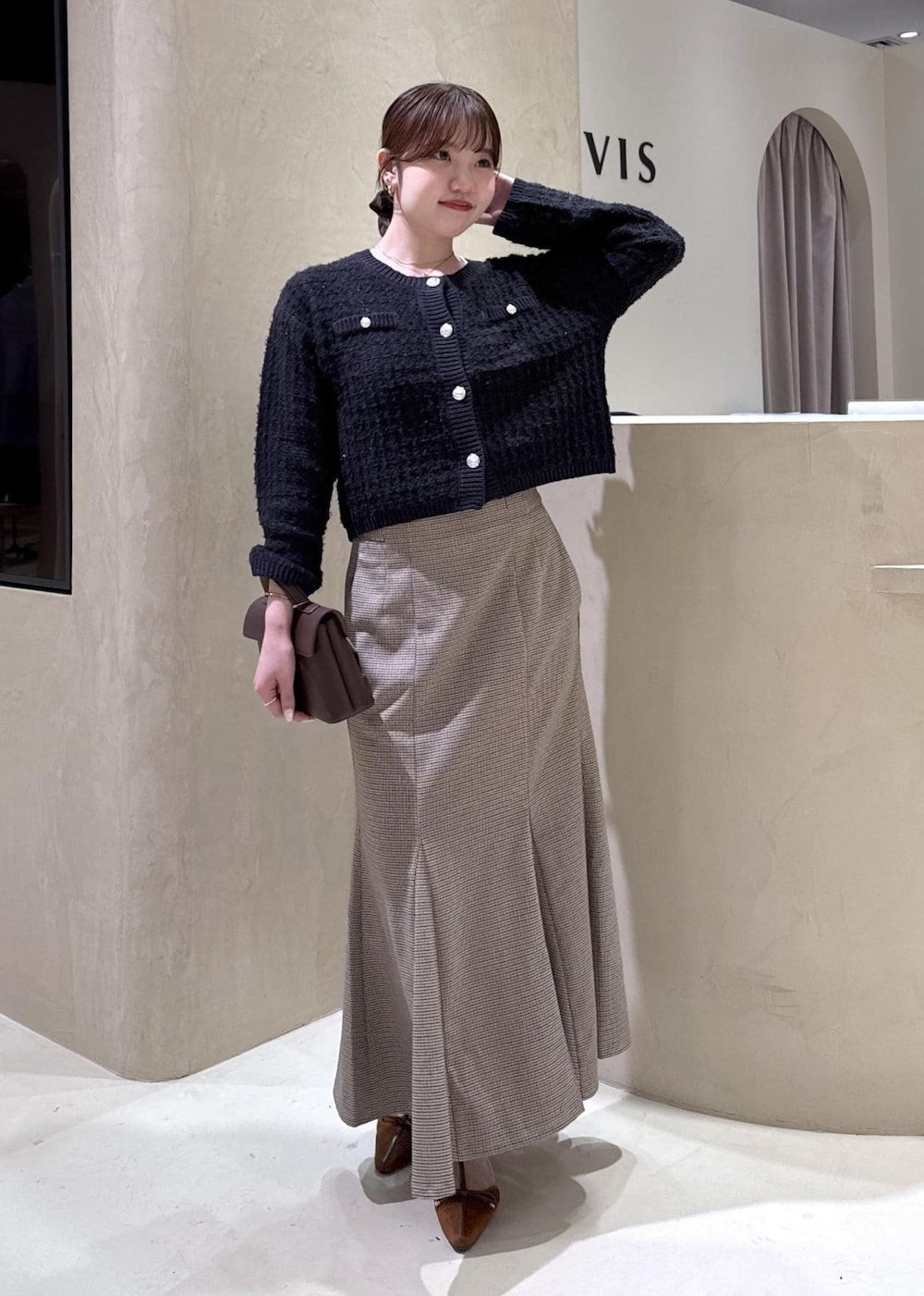 ブラウン系のショルダーバッグ、イエロー系のパンプス、ベージュ系のスカートを着用したレディースの秋コーディネートの2枚目の写真