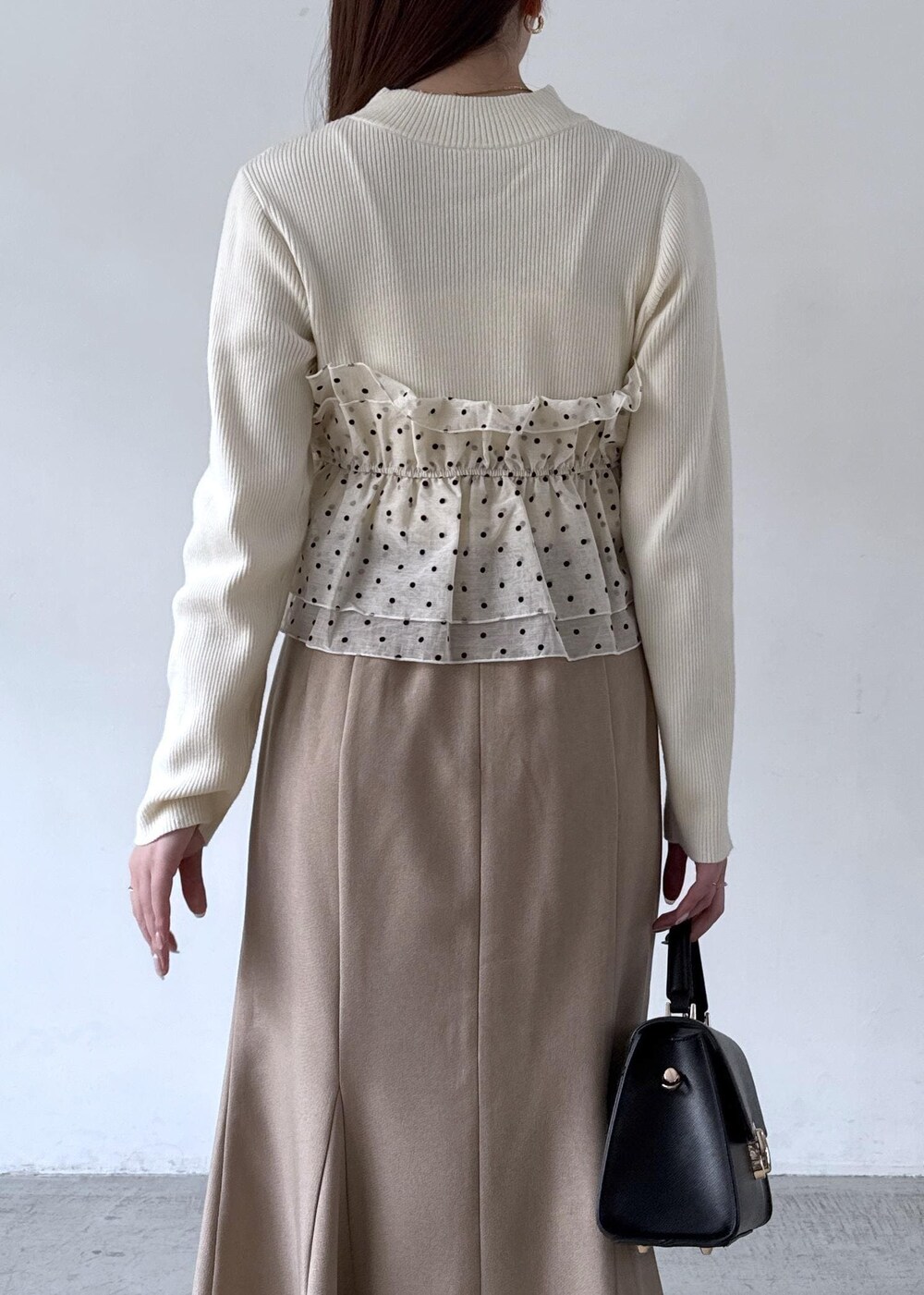 ホワイト系のキャミソール、ベージュ系のスカート、ブラック系のブーツを着用したレディースの秋コーディネートの5枚目の写真