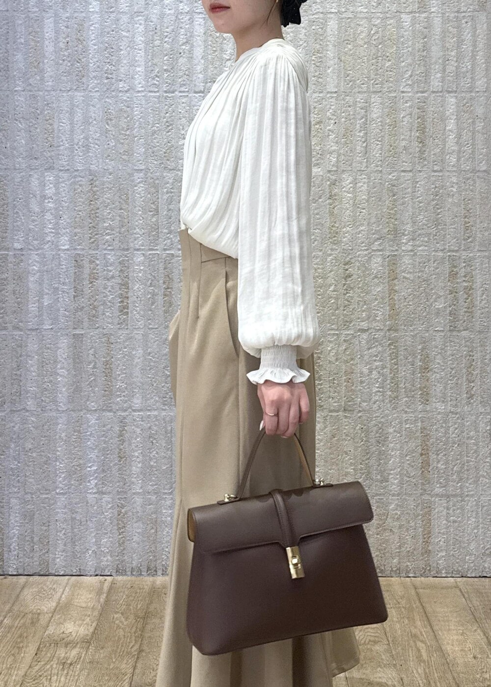 ブラウン系のハンドバッグ、イエロー系のパンプス、ベージュ系のスカートを着用したレディースの秋コーディネートの4枚目の写真