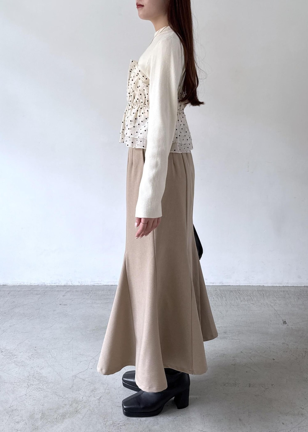 ホワイト系のキャミソール、ベージュ系のスカート、ブラック系のブーツを着用したレディースの秋コーディネートの4枚目の写真