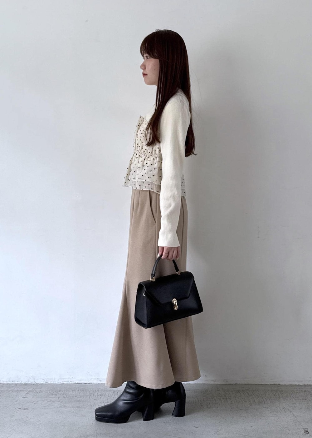 ホワイト系のキャミソール、ベージュ系のスカート、ブラック系のブーツを着用したレディースの秋コーディネートの3枚目の写真