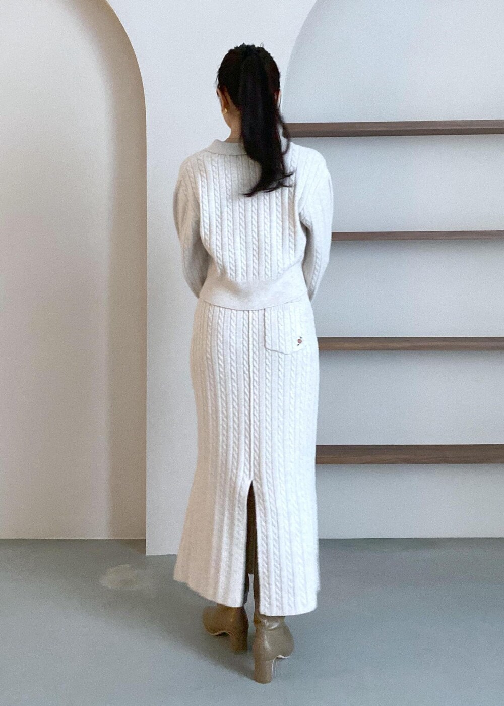 グリーン系のショルダーバッグ、ベージュ系のブーツ、ベージュ系のスカートを着用したレディースの冬コーディネートの7枚目の写真