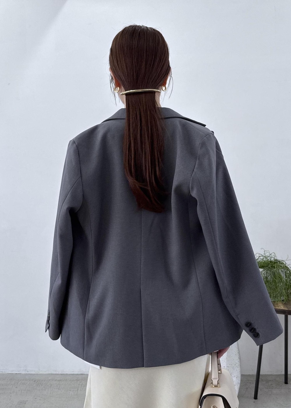 グレー系のテーラードジャケット、ブラック系のブーツ、ホワイト系のスカートを着用したレディースの秋コーディネートの8枚目の写真