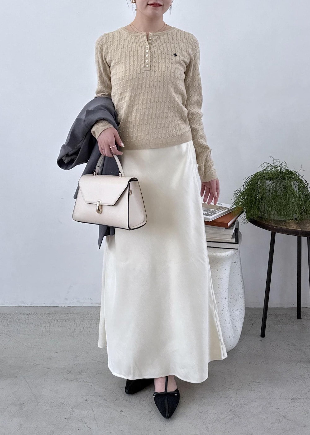 グレー系のテーラードジャケット、ブラック系のブーツ、ホワイト系のスカートを着用したレディースの秋コーディネートの3枚目の写真