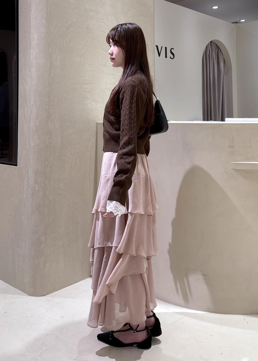 ブラック系のパンプス、ピンク系のスカート、ブラウン系のカーディガン/ボレロを着用したレディースの秋コーディネートの5枚目の写真