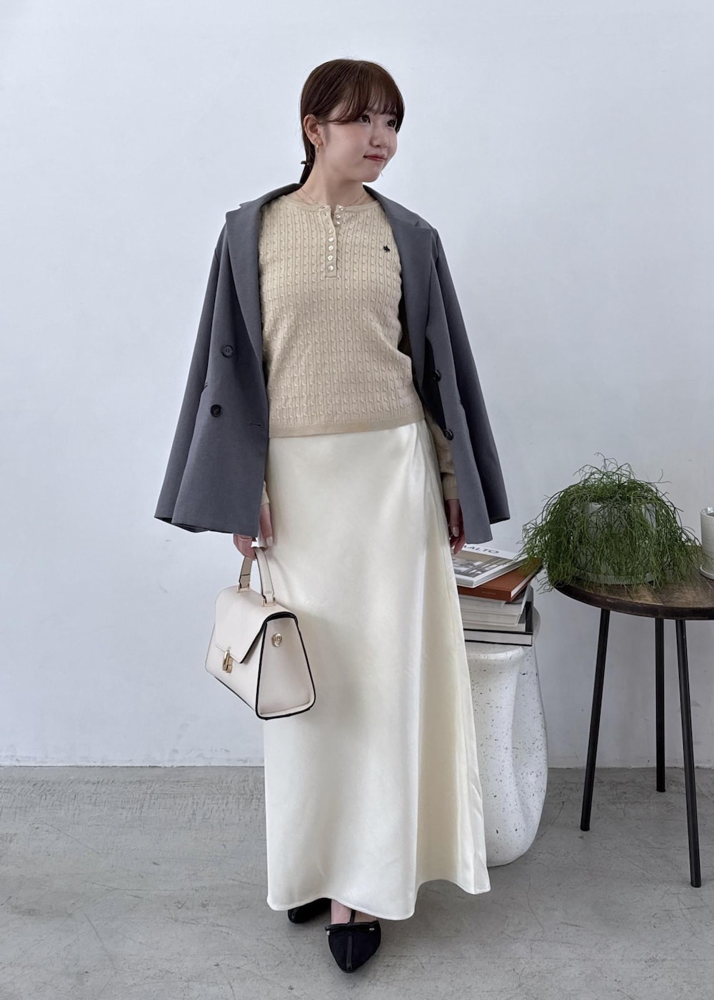 グレー系のテーラードジャケット、ブラック系のブーツ、ホワイト系のスカートを着用したレディースの秋コーディネートの2枚目の写真