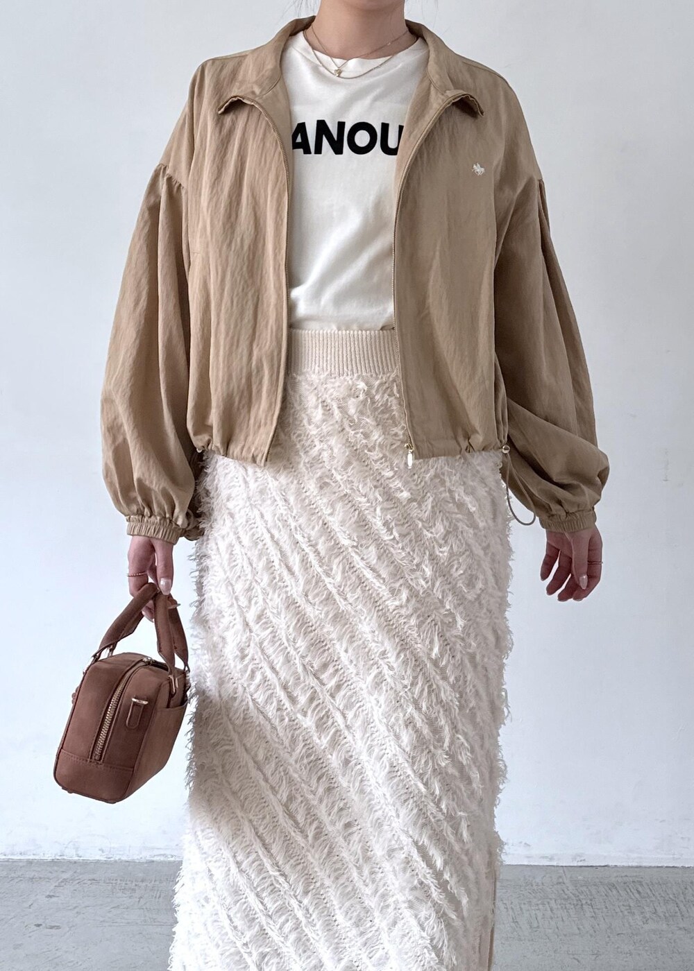 ブラウン系のボストンバッグ、ホワイト系のTシャツ/カットソー、ベージュ系のブルゾンを着用したレディースの秋コーディネートの3枚目の写真