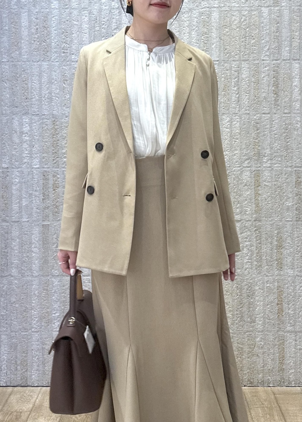 ブラウン系のハンドバッグ、イエロー系のパンプス、ベージュ系のスカートを着用したレディースの秋コーディネートの6枚目の写真