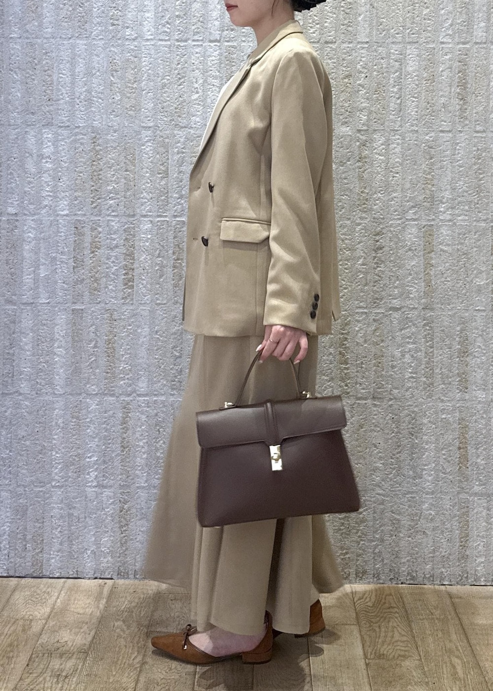 ブラウン系のハンドバッグ、イエロー系のパンプス、ベージュ系のスカートを着用したレディースの秋コーディネートの9枚目の写真