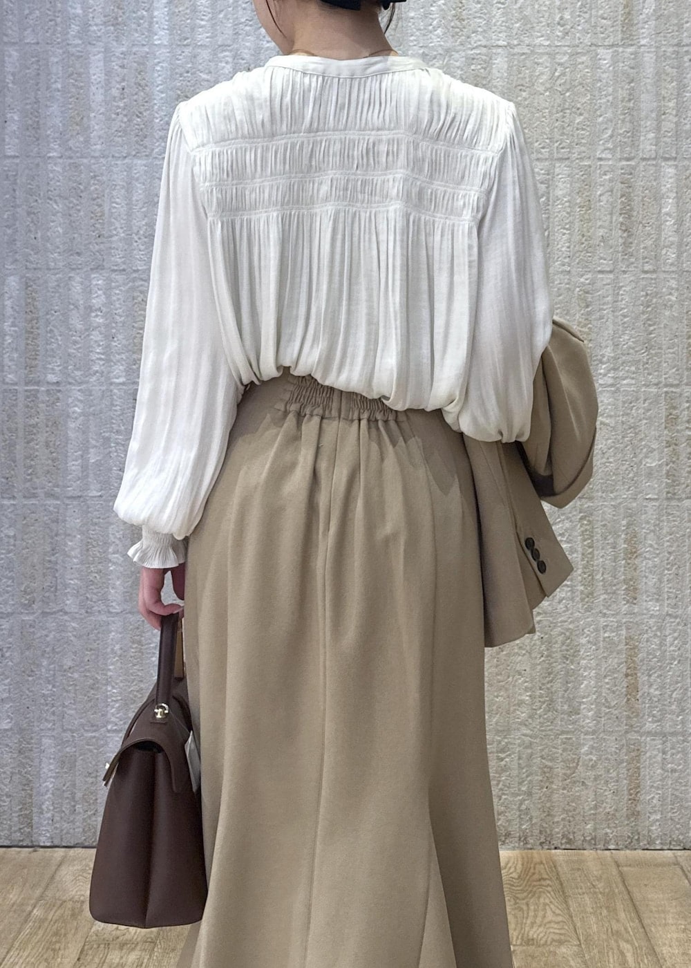 ブラウン系のハンドバッグ、イエロー系のパンプス、ベージュ系のスカートを着用したレディースの秋コーディネートの5枚目の写真