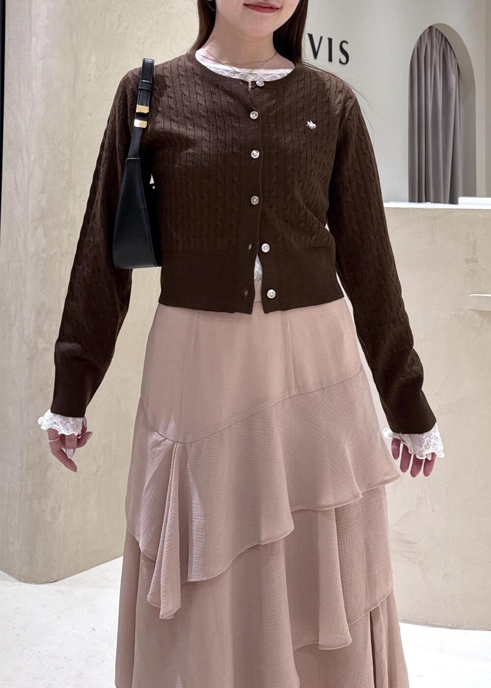 ブラック系のパンプス、ピンク系のスカート、ブラウン系のカーディガン/ボレロを着用したレディースの秋コーディネートの3枚目の写真