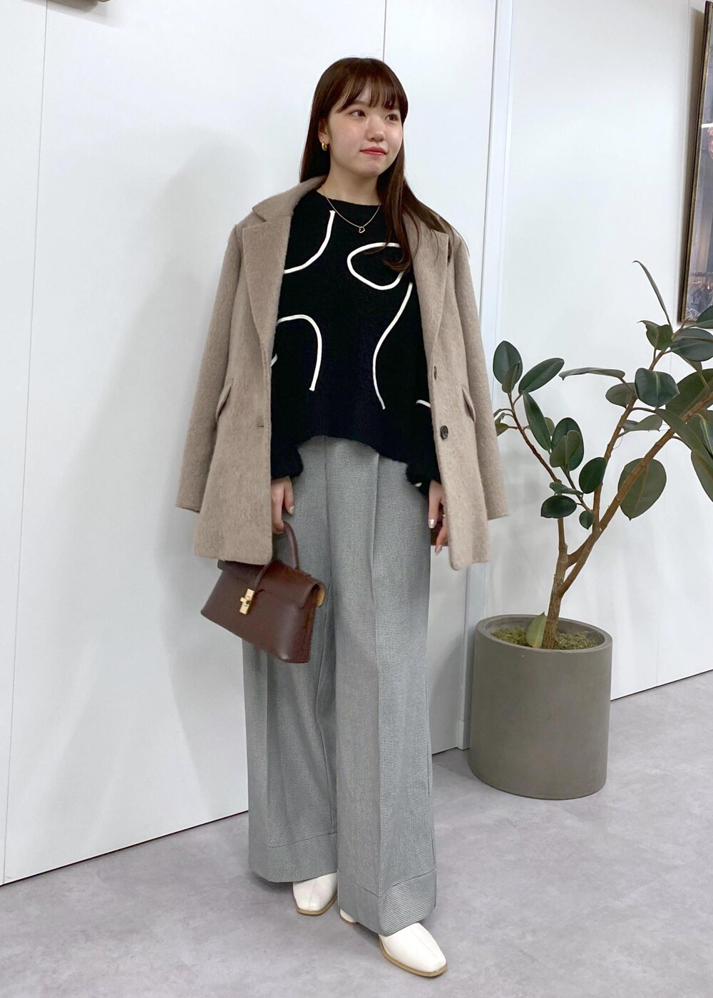 ホワイト系のブーツ、ブラック系のニット/セーター、ブラウン系のその他アウターを着用したレディースの秋コーディネートの2枚目の写真