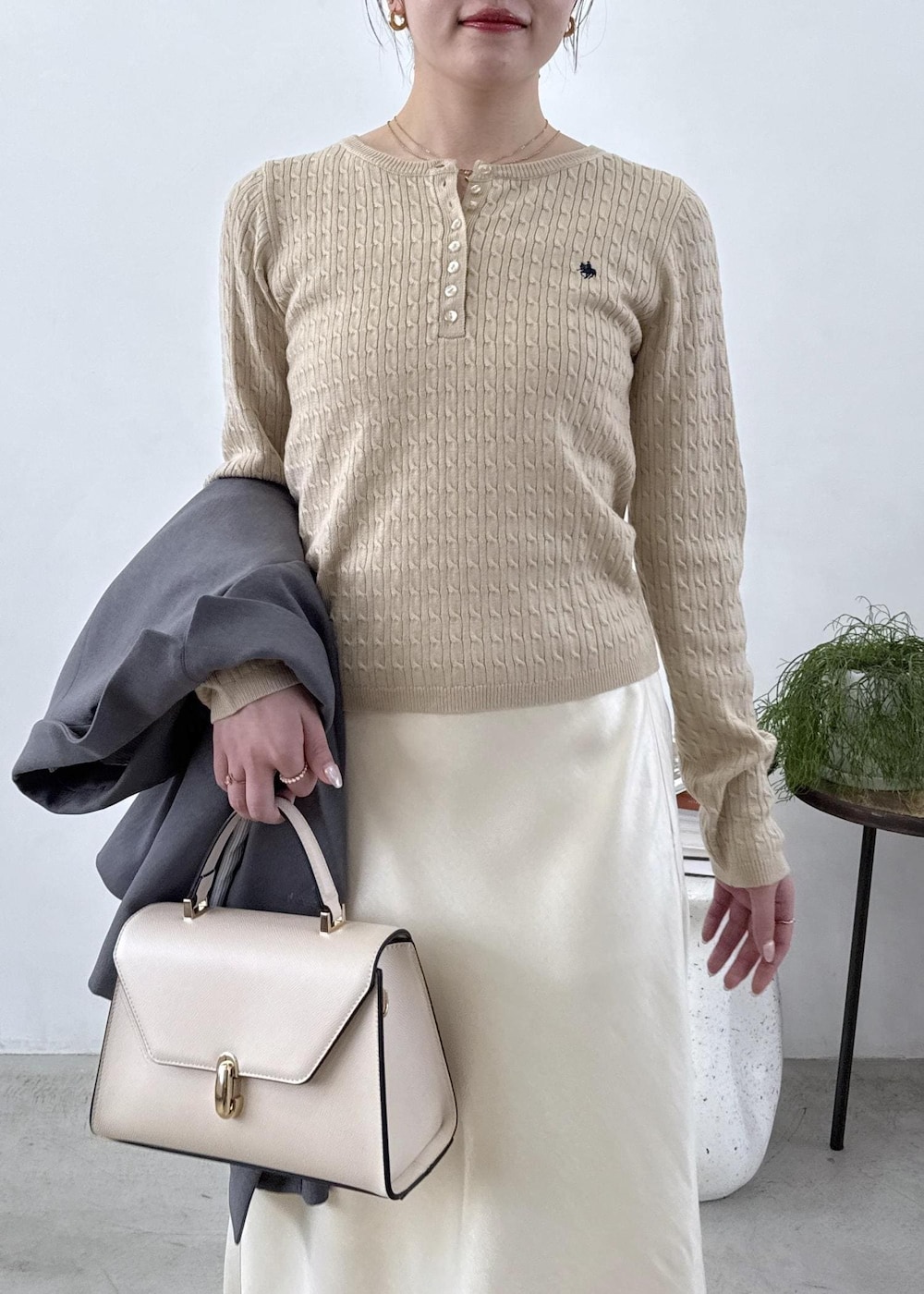 グレー系のテーラードジャケット、ブラック系のブーツ、ホワイト系のスカートを着用したレディースの秋コーディネートの4枚目の写真