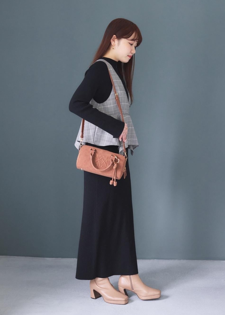 ホワイト系のキャミソール、ブラウン系のボストンバッグ、ベージュ系のブーツを着用したレディースの秋コーディネートの3枚目の写真