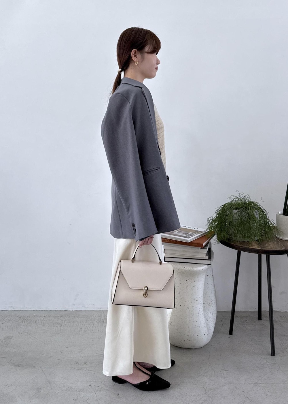 グレー系のテーラードジャケット、ブラック系のブーツ、ホワイト系のスカートを着用したレディースの秋コーディネートの6枚目の写真