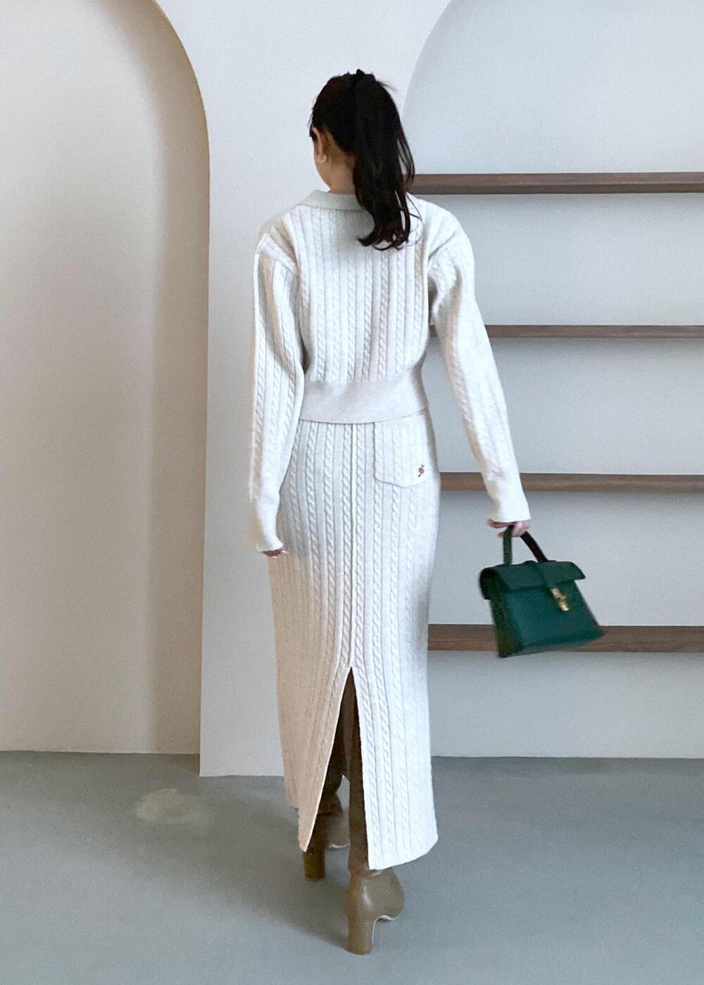 グリーン系のショルダーバッグ、ベージュ系のブーツ、ベージュ系のスカートを着用したレディースの冬コーディネートの6枚目の写真