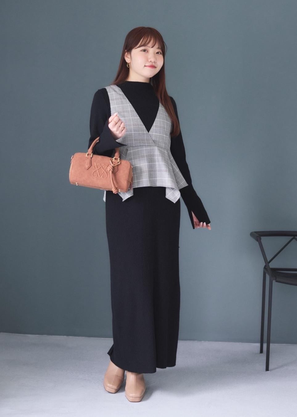 ホワイト系のキャミソール、ブラウン系のボストンバッグ、ベージュ系のブーツを着用したレディースの秋コーディネートの2枚目の写真