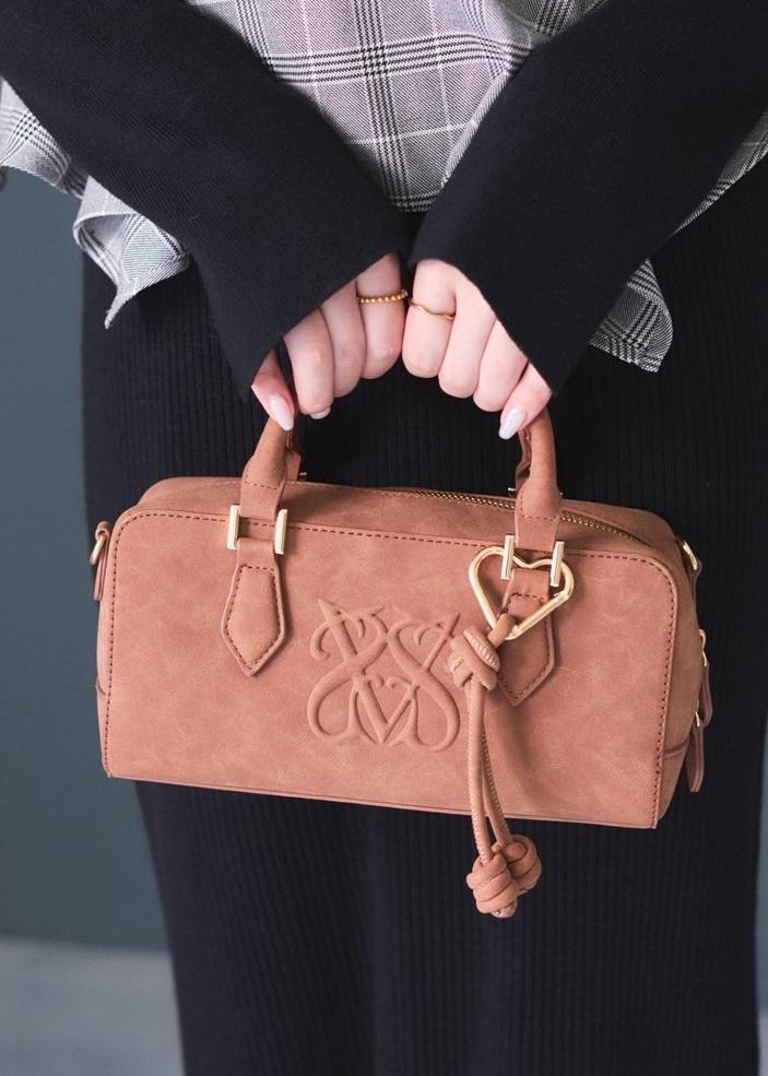 ホワイト系のキャミソール、ブラウン系のボストンバッグ、ベージュ系のブーツを着用したレディースの秋コーディネートの5枚目の写真