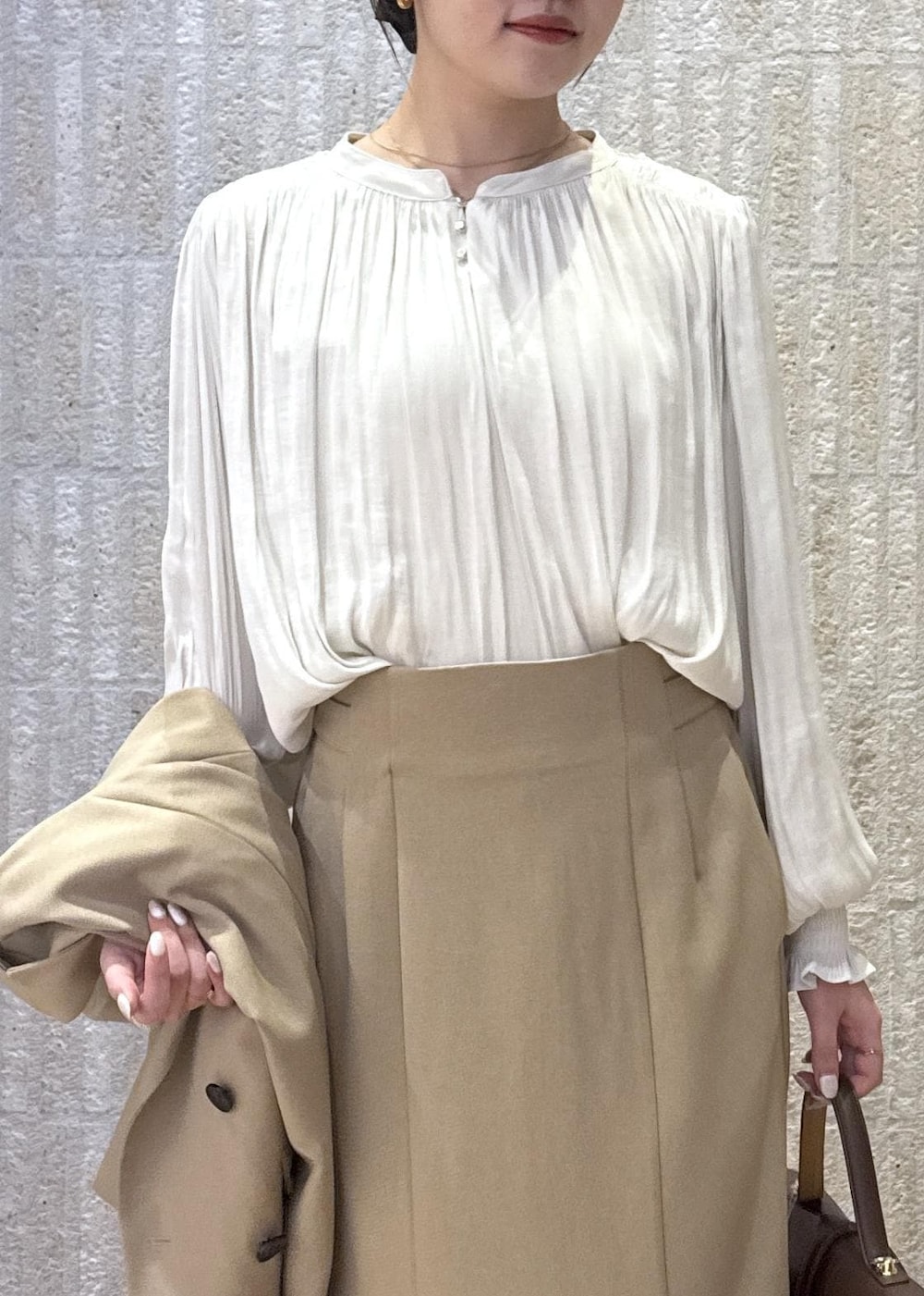 ブラウン系のハンドバッグ、イエロー系のパンプス、ベージュ系のスカートを着用したレディースの秋コーディネートの3枚目の写真