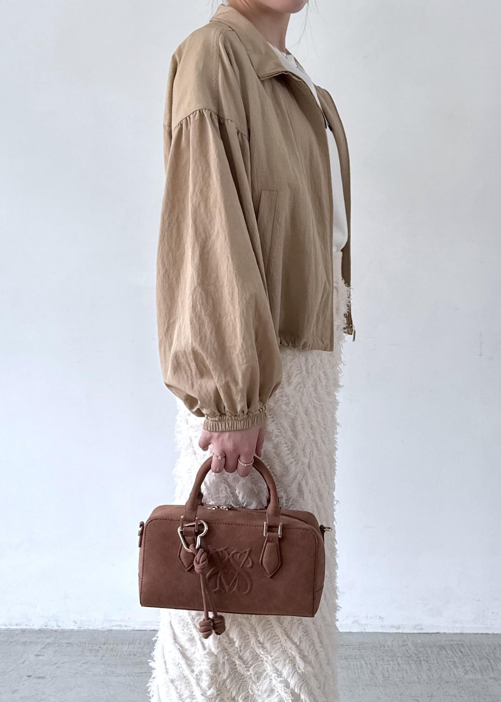 ブラウン系のボストンバッグ、ホワイト系のTシャツ/カットソー、ベージュ系のブルゾンを着用したレディースの秋コーディネートの4枚目の写真