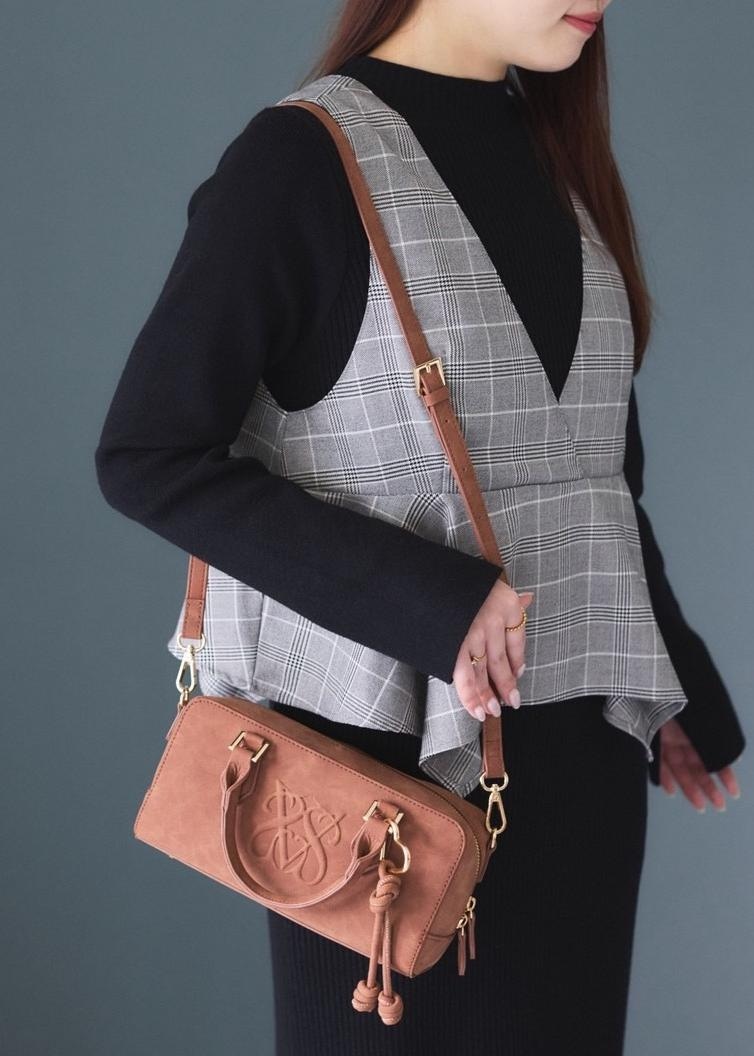 ホワイト系のキャミソール、ブラウン系のボストンバッグ、ベージュ系のブーツを着用したレディースの秋コーディネートの6枚目の写真