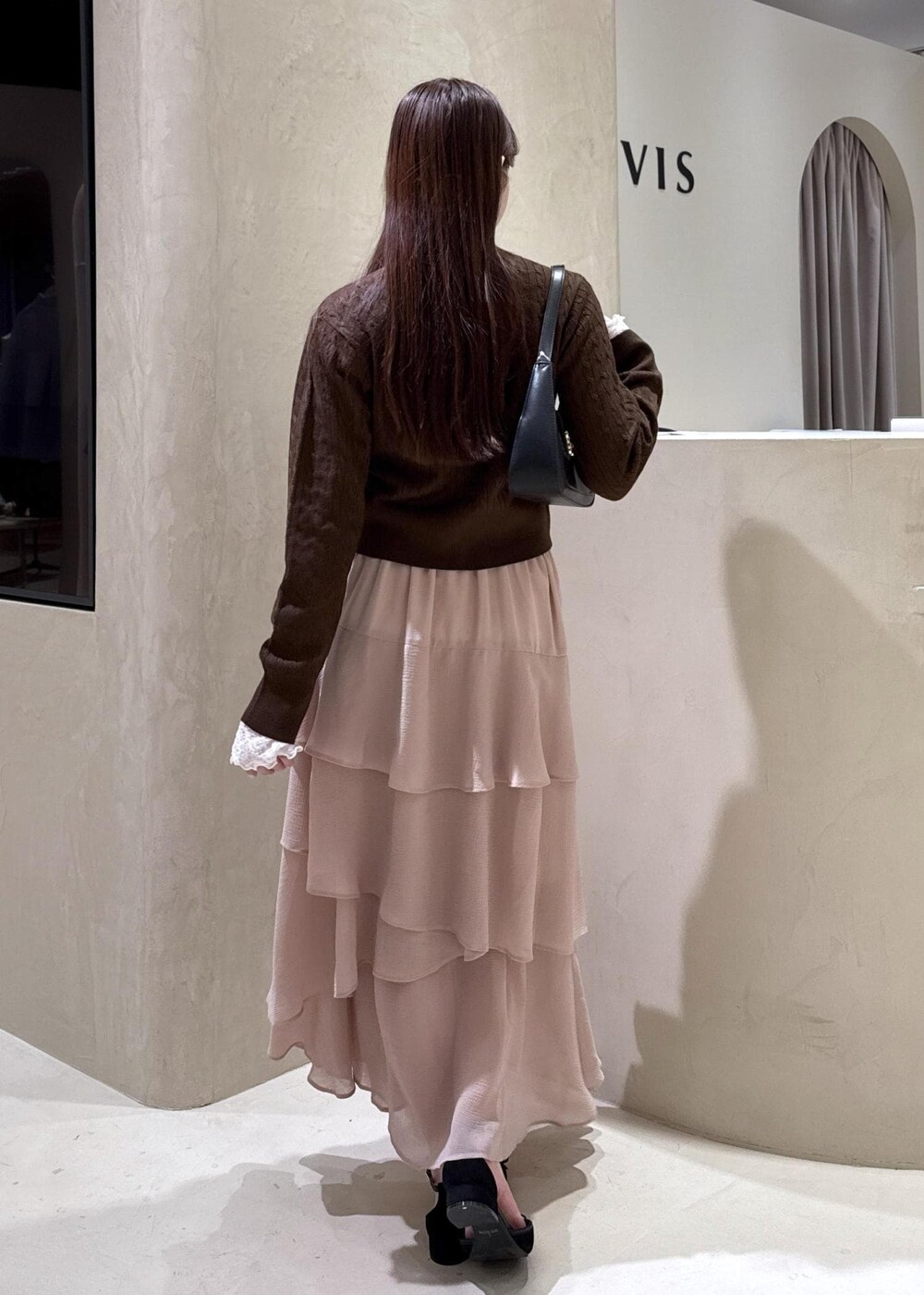 ブラック系のパンプス、ピンク系のスカート、ブラウン系のカーディガン/ボレロを着用したレディースの秋コーディネートの7枚目の写真