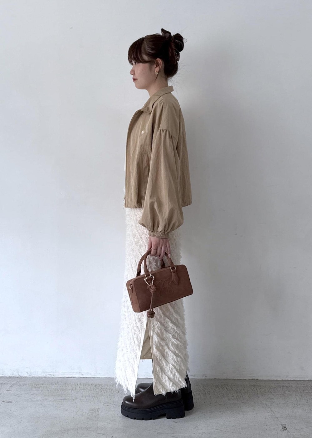 ブラウン系のボストンバッグ、ホワイト系のTシャツ/カットソー、ベージュ系のブルゾンを着用したレディースの秋コーディネートの5枚目の写真