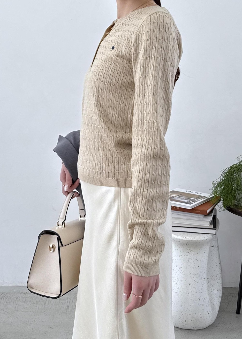 グレー系のテーラードジャケット、ブラック系のブーツ、ホワイト系のスカートを着用したレディースの秋コーディネートの5枚目の写真