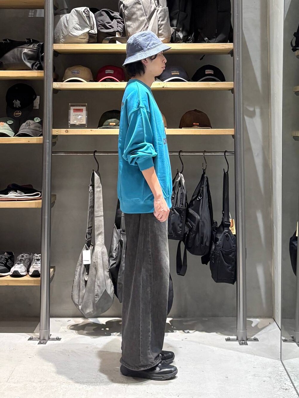 グレー系のデニムパンツ、ブルー系のハットを着用したメンズの秋コーディネートの2枚目の写真