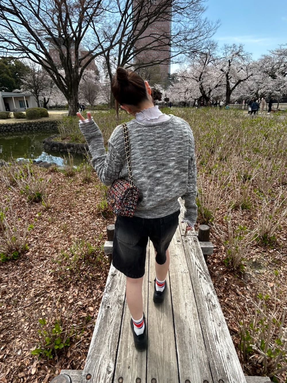 グレー系のカーディガン/ボレロ、ブラック系のデニムパンツ、ブラック系のスニーカーを着用したレディースの春コーディネートの2枚目の写真