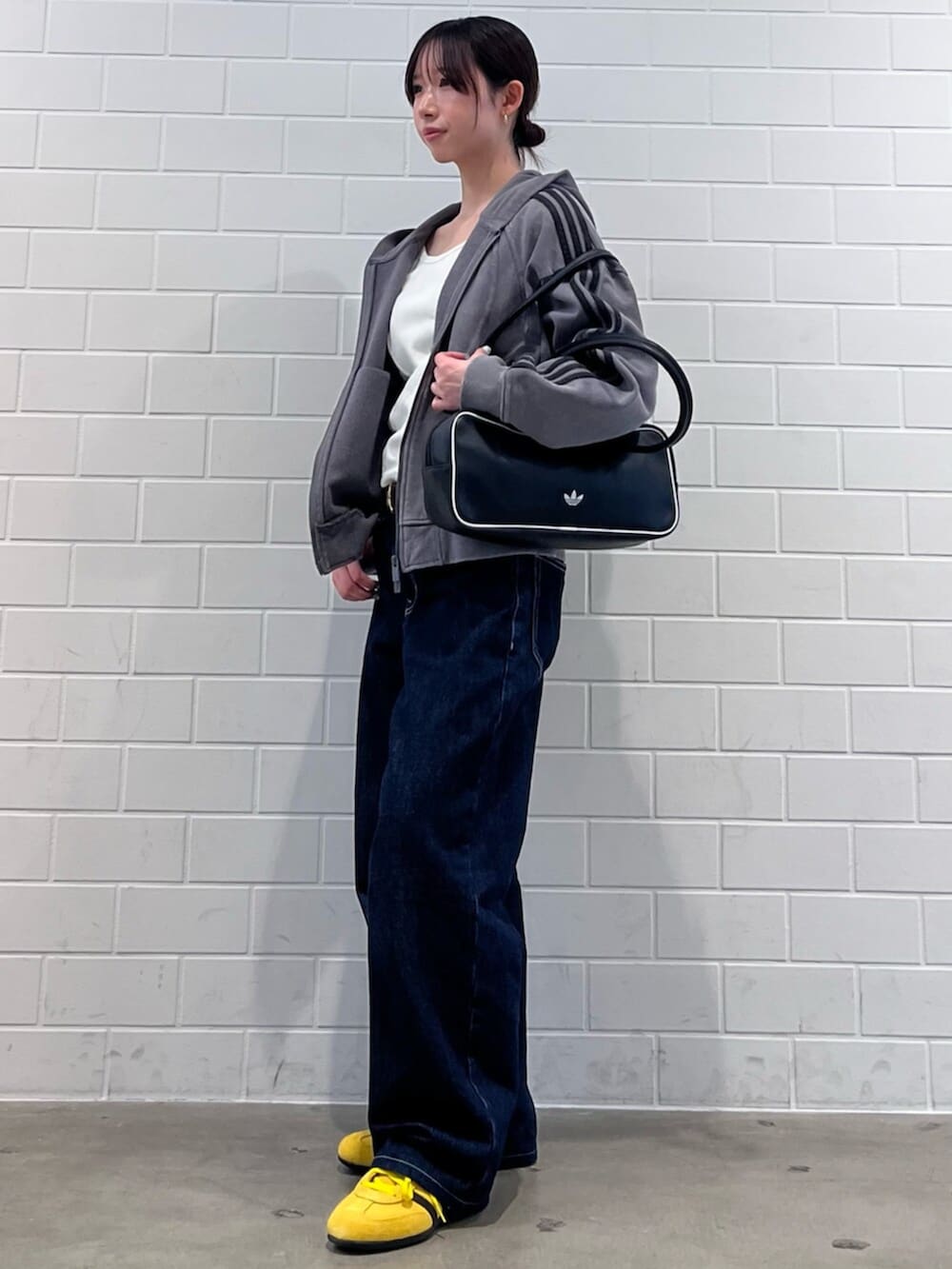 ブラック系のショルダーバッグ、イエロー系のスニーカー、グレー系のパーカーを着用したレディースの冬コーディネートの3枚目の写真