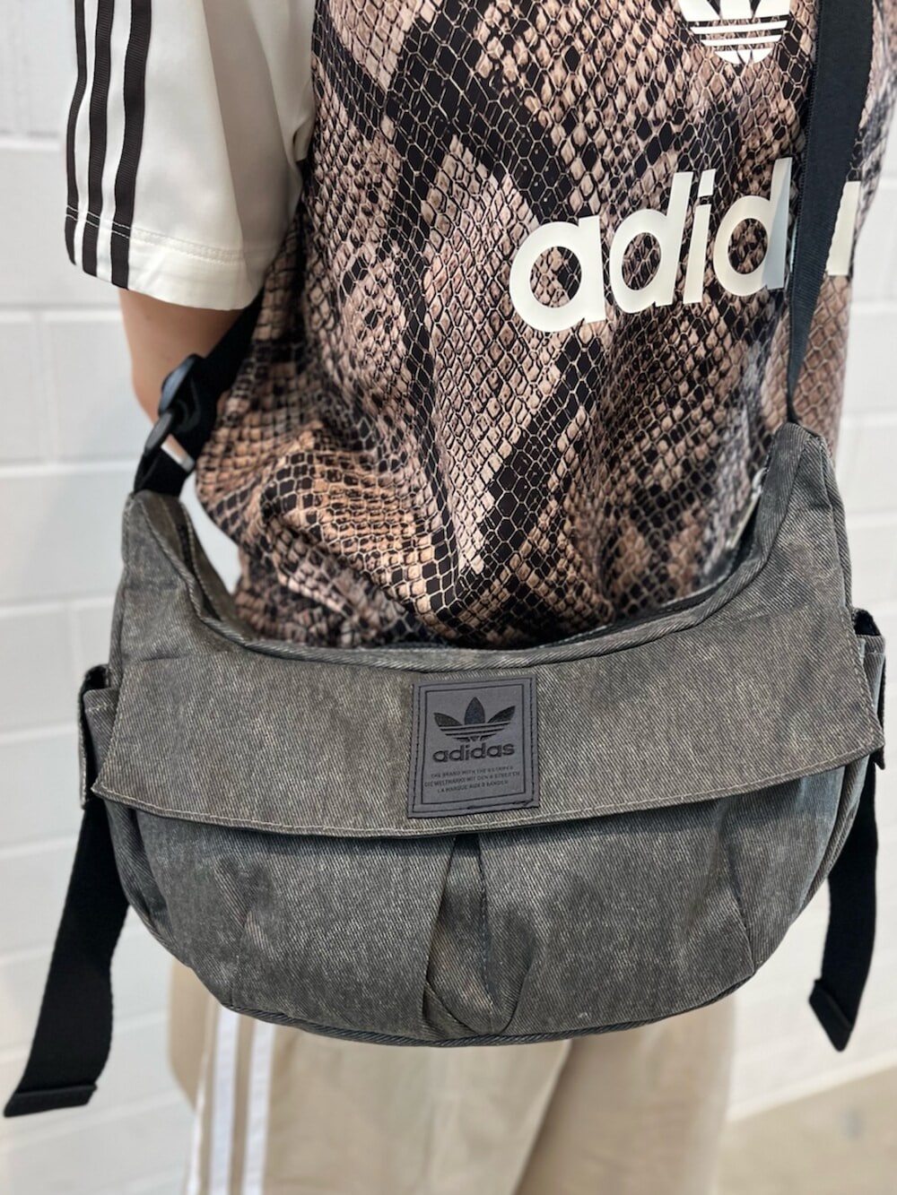 ブラウン系のスニーカー、ベージュ系のトップス、ブラック系のショルダーバッグを着用したレディースの夏コーディネートの4枚目の写真
