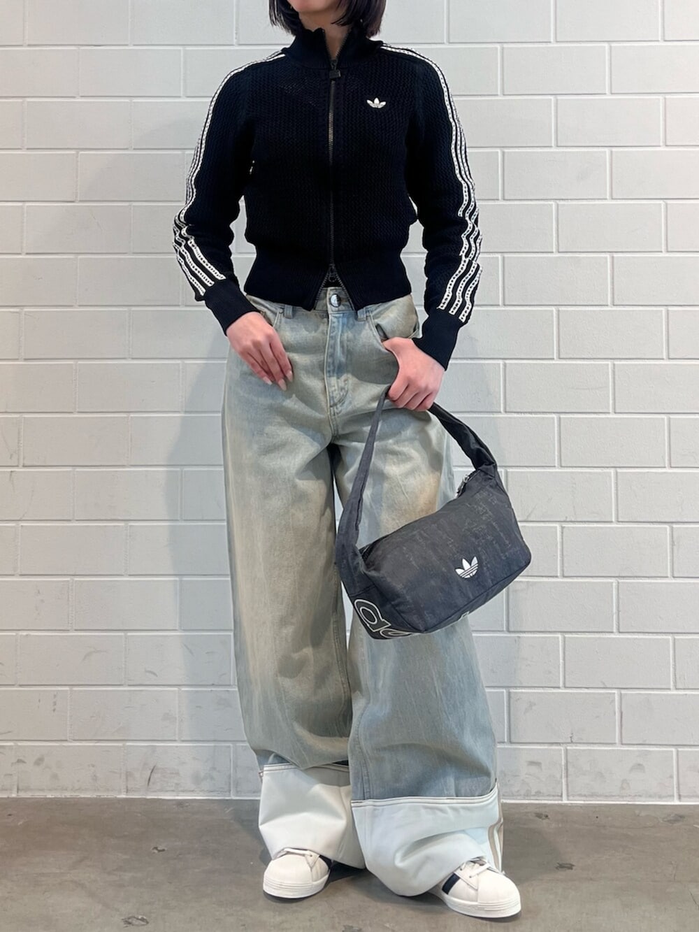 ブルー系のデニムパンツ、ホワイト系のシューズ、ブラック系のショルダーバッグを着用したレディースの春コーディネートの2枚目の写真