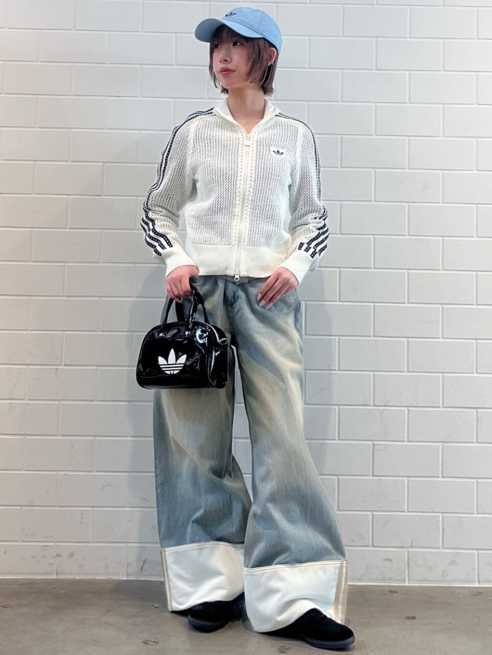 ブラック系のショルダーバッグ、ブラック系のスニーカー、ブルー系のデニムパンツを着用したレディースの春コーディネートの3枚目の写真