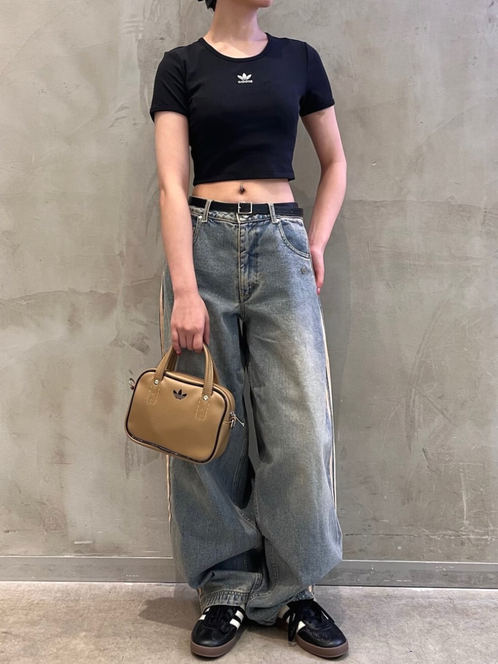 ブラック系のTシャツ/カットソー、ベージュ系のショルダーバッグ、ブルー系のデニムパンツを着用したレディースの秋コーディネートの2枚目の写真