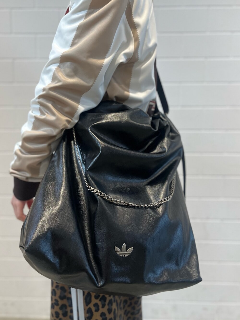 ブラック系のショルダーバッグ、ブラック系のスニーカー、ホワイト系のトップスを着用したレディースの冬コーディネートの6枚目の写真