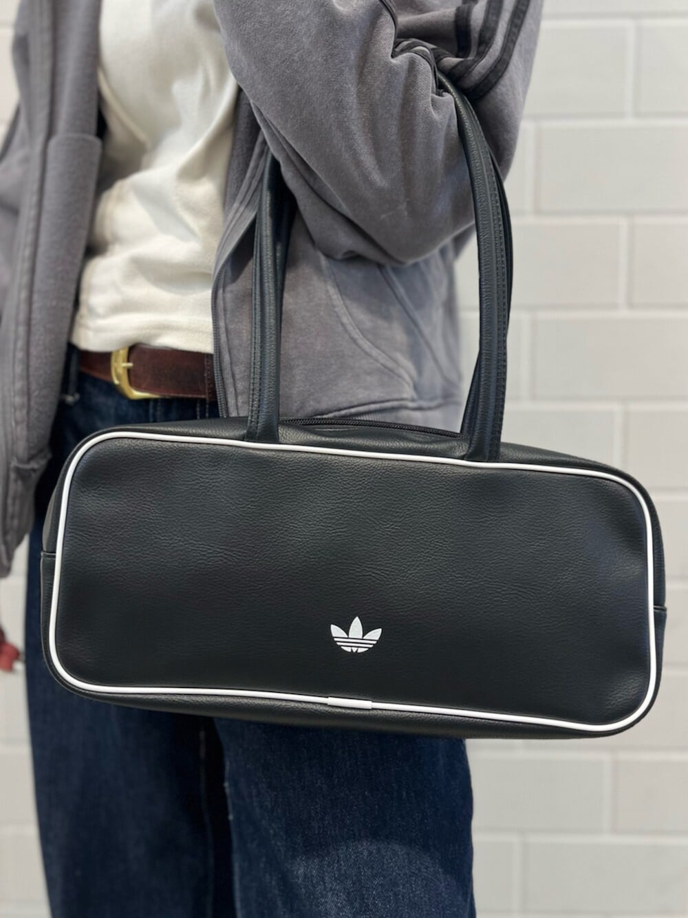 ブラック系のショルダーバッグ、イエロー系のスニーカー、グレー系のパーカーを着用したレディースの冬コーディネートの5枚目の写真