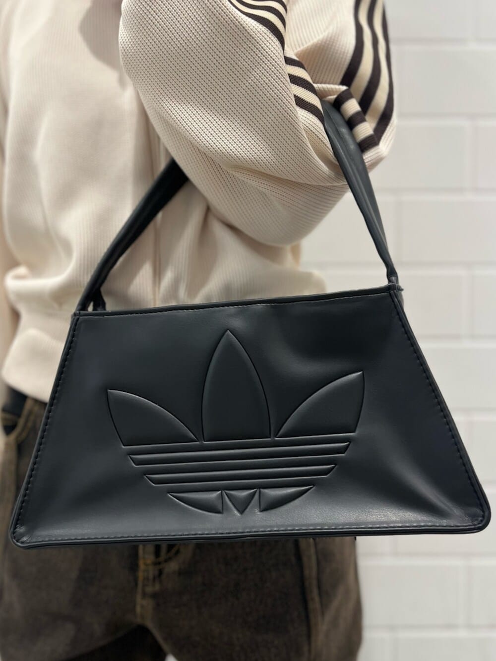 ブラック系のショルダーバッグ、ホワイト系のジャージ、ブラウン系のパンツを着用したレディースの冬コーディネートの4枚目の写真