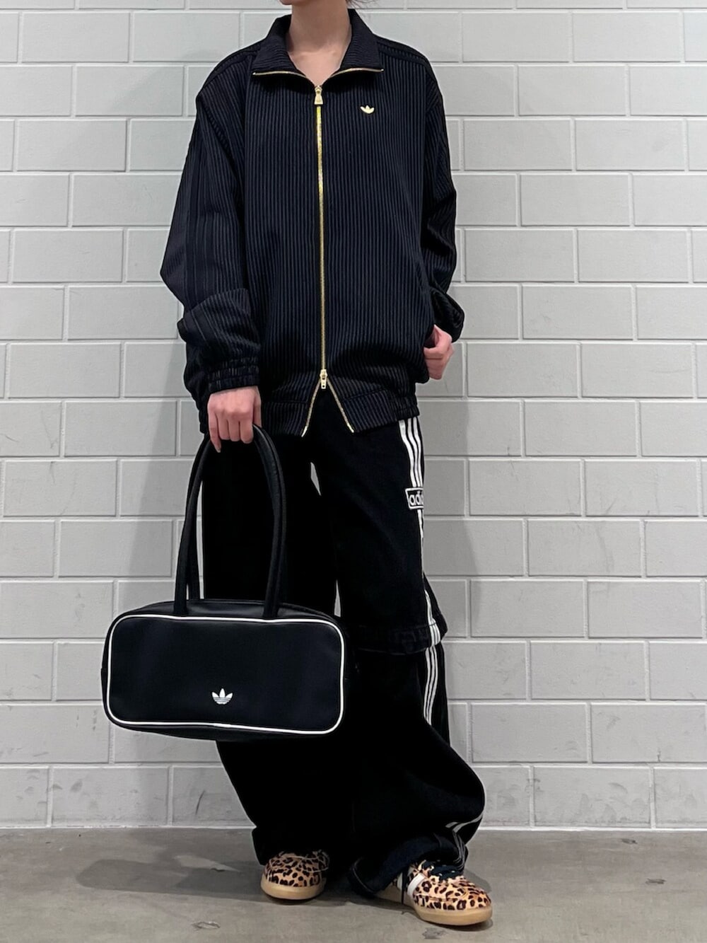 ブラック系のショルダーバッグ、ベージュ系のスニーカー、ブラック系のジャージを着用したレディースの冬コーディネートの2枚目の写真