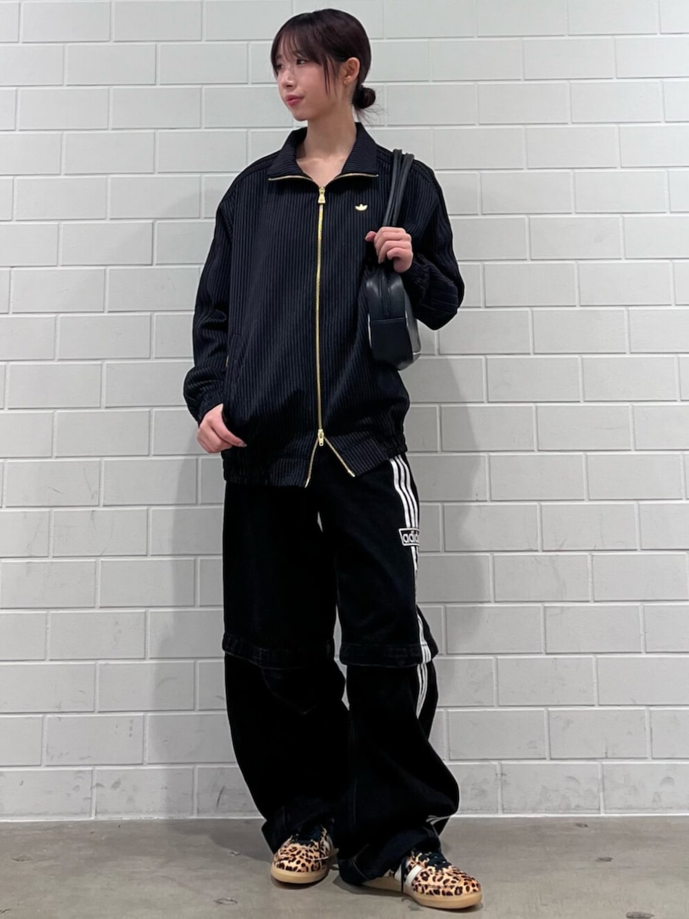 ブラック系のショルダーバッグ、ベージュ系のスニーカー、ブラック系のジャージを着用したレディースの冬コーディネートの3枚目の写真