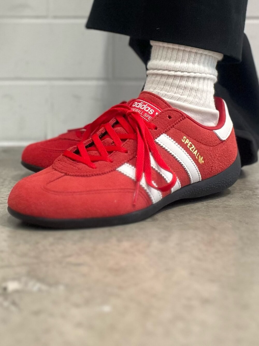 レッド系のスニーカー、ブラック系のショルダーバッグ、ホワイト系のポロシャツを着用したレディースの春コーディネートの6枚目の写真