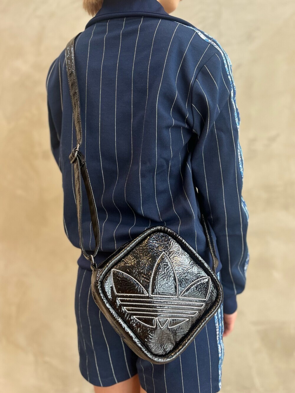 ブラック系のショルダーバッグ、ブラック系のスニーカー、ブルー系のトップスを着用したレディースの春コーディネートの5枚目の写真