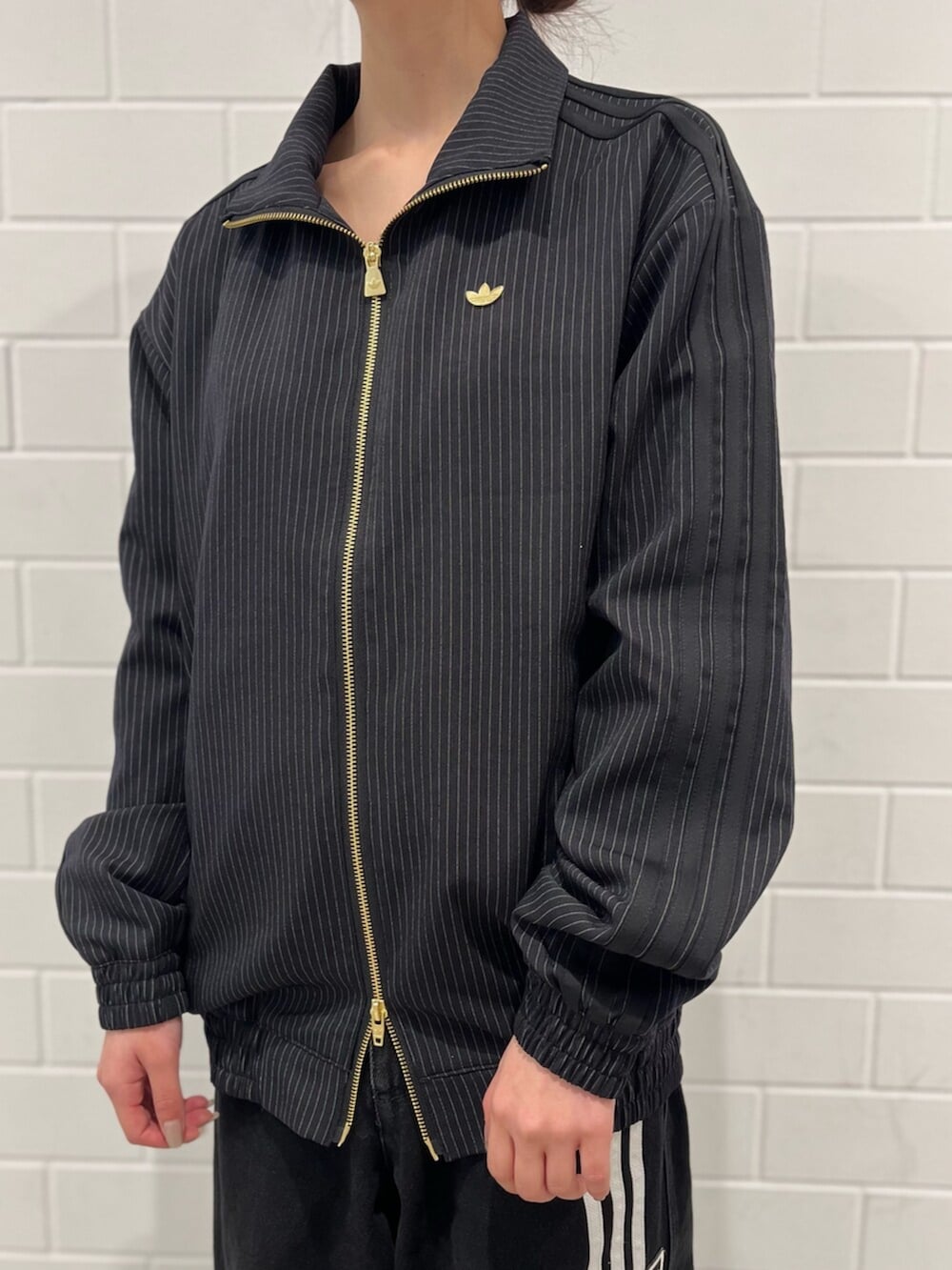 ブラック系のショルダーバッグ、ベージュ系のスニーカー、ブラック系のジャージを着用したレディースの冬コーディネートの4枚目の写真